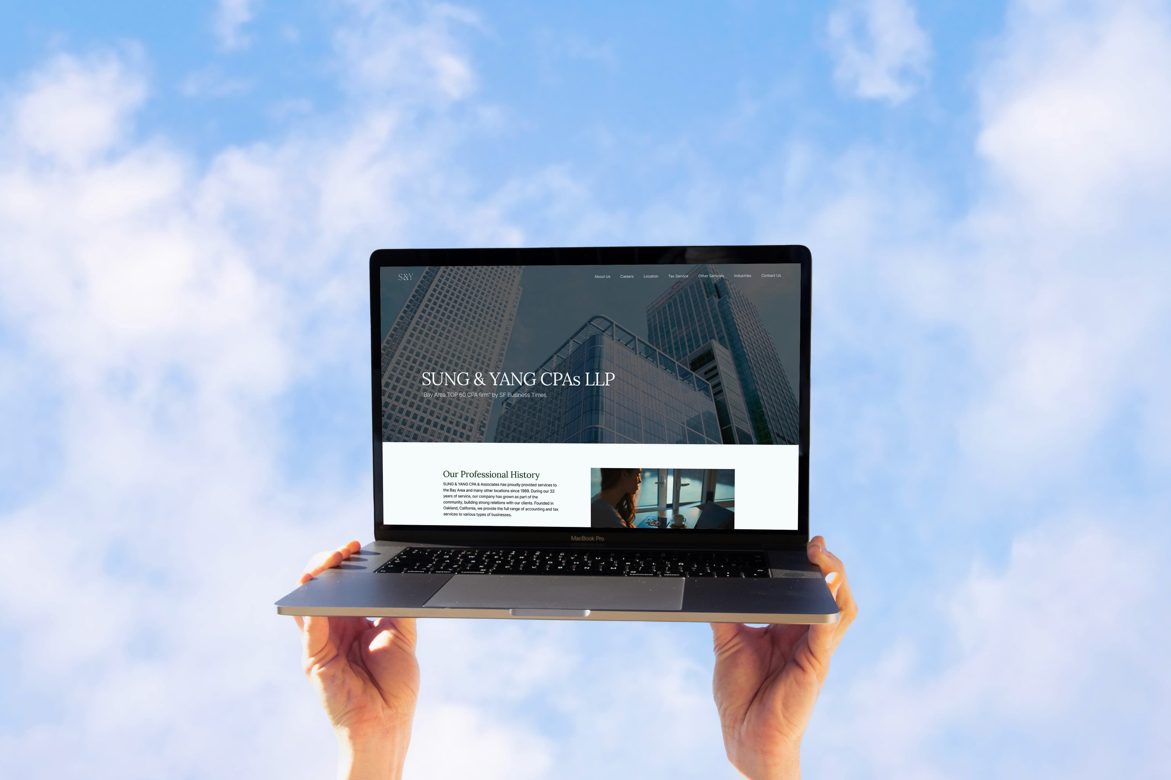 Laptop held up against the sky, showing the Sung & Yang CPAs website